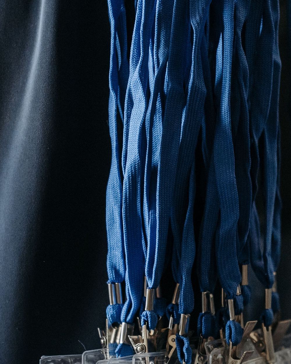Beveiligerspassen aan blauwe koorden aan een rek, de namen onleesbaar.